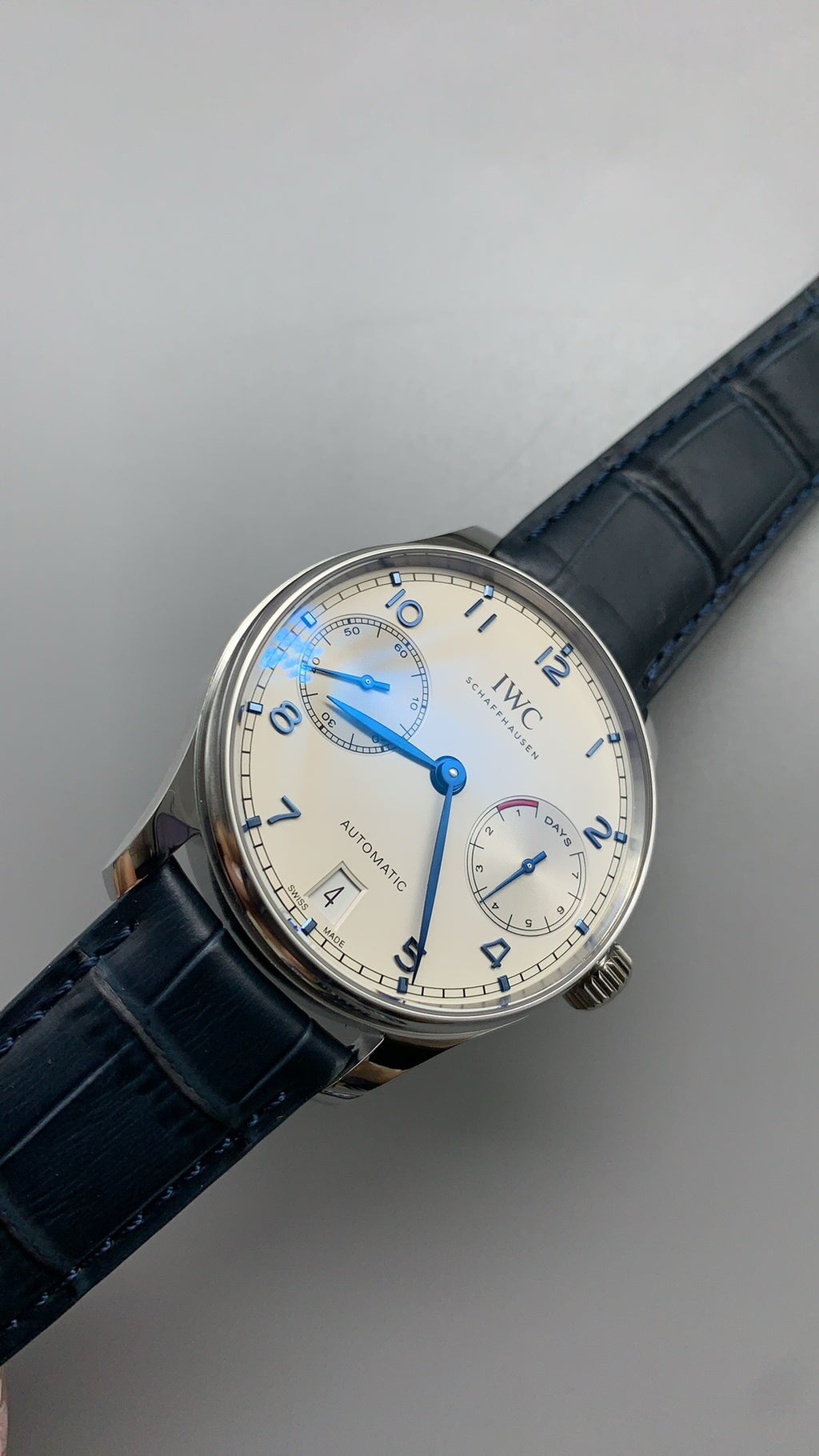 IWC Portugieser Automatic IW500705 | 42.3MM | ตัวเรือนสเตนเลสสตีล | หน้าปัดสีขาว | เข็มสีน้ำเงิน | สายหนังจระเข้สีน้ำเงิน | กลไกอัตโนมัติ Cal.52010