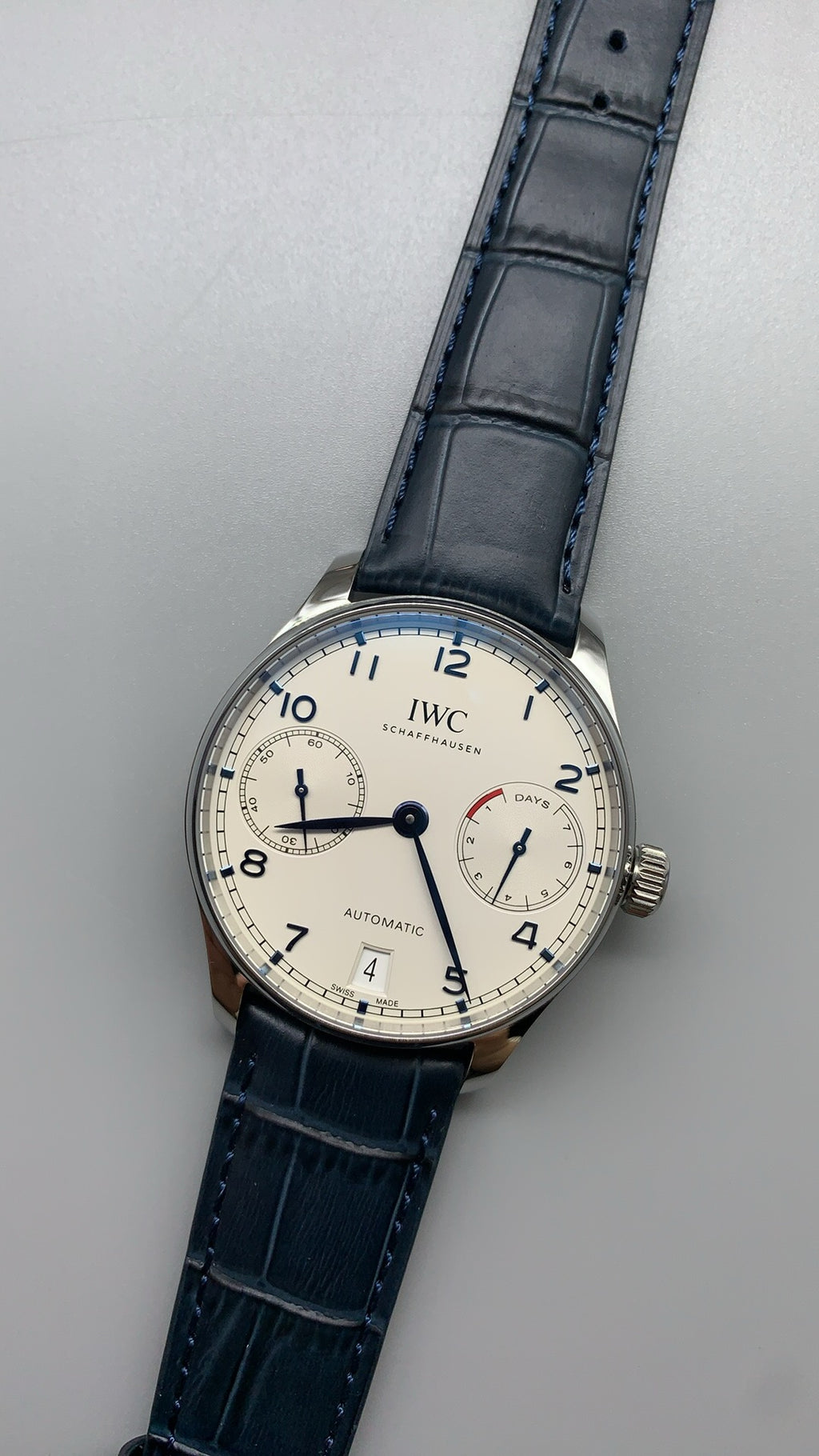 IWC Portugieser Automatic IW500705 | 42.3MM | ตัวเรือนสเตนเลสสตีล | หน้าปัดสีขาว | เข็มสีน้ำเงิน | สายหนังจระเข้สีน้ำเงิน | กลไกอัตโนมัติ Cal.52010